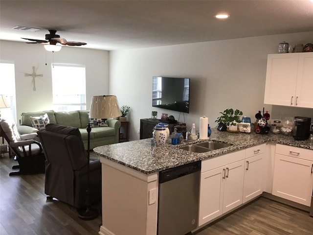 kitchen featuring a peninsula, a sink, dishwasher, dark stone countertops, and dark wood finished floors