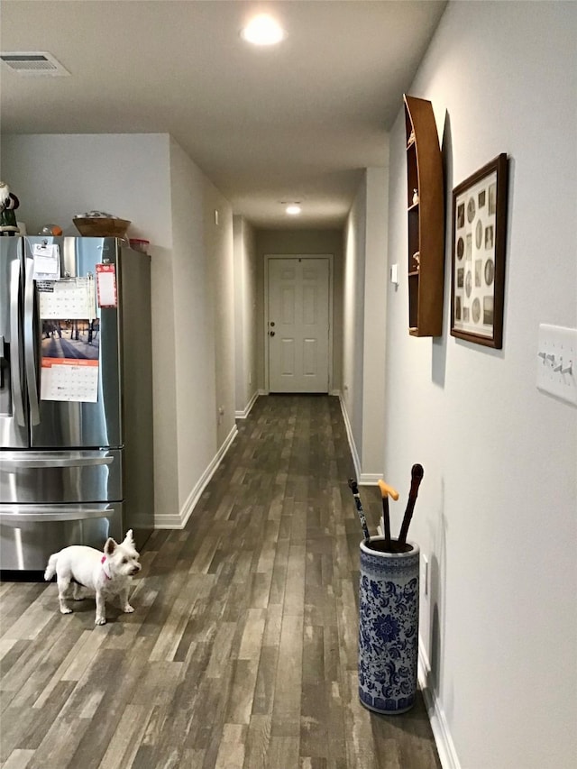 hallway with dark wood-style floors, visible vents, and baseboards