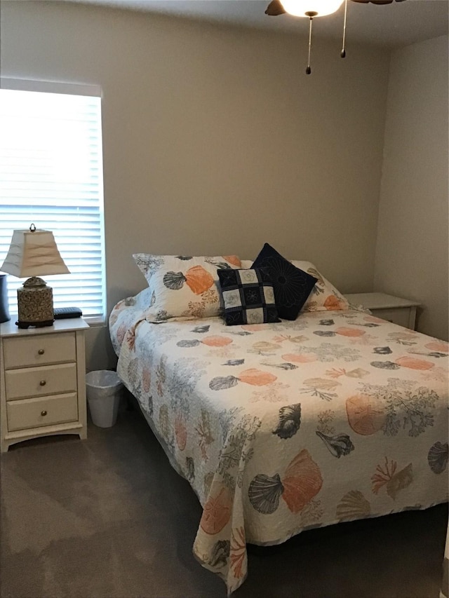 bedroom featuring multiple windows, dark carpet, and a ceiling fan