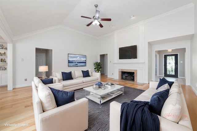 living area with high vaulted ceiling, light wood finished floors, a tile fireplace, and baseboards