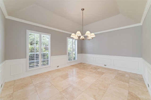 empty room featuring ornamental molding, wainscoting, and an inviting chandelier