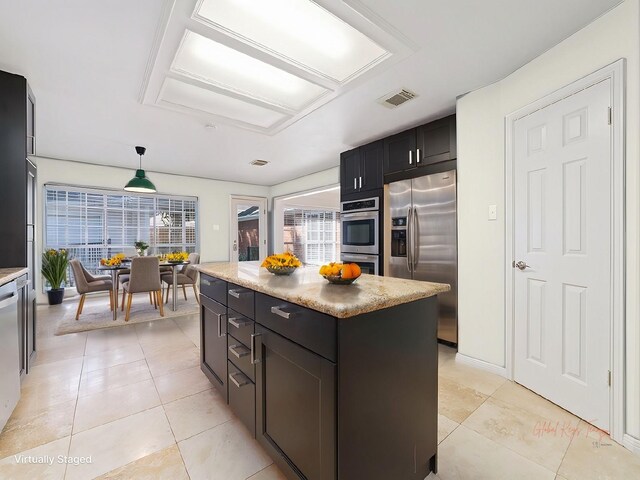 kitchen featuring stainless steel appliances, a kitchen island, visible vents, hanging light fixtures, and light countertops