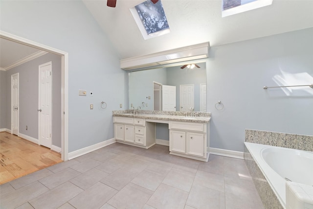 bathroom featuring a sink, lofted ceiling with skylight, a garden tub, and a ceiling fan