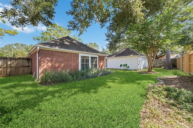 rear view of property with brick siding, a yard, and a fenced backyard