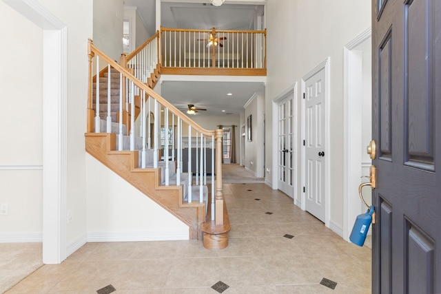 entryway featuring tile patterned flooring, stairway, a high ceiling, and baseboards