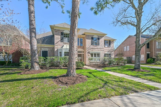 colonial home featuring brick siding and a front yard