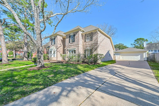 view of front of home with a garage, brick siding, an outbuilding, fence, and a front yard