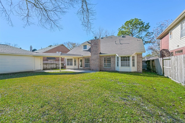 back of property featuring a shingled roof, a fenced backyard, a yard, a patio area, and brick siding