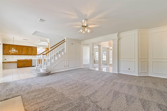 unfurnished living room with stairs, a wealth of natural light, light colored carpet, and a decorative wall