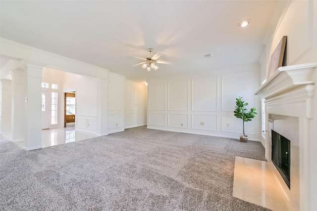 unfurnished living room featuring a decorative wall, a fireplace, ornamental molding, carpet, and decorative columns