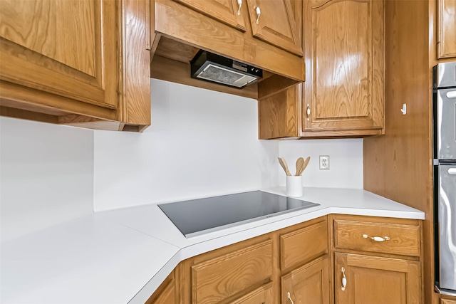 kitchen featuring stainless steel double oven, light countertops, under cabinet range hood, and black electric stovetop