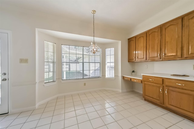 kitchen featuring built in study area, brown cabinets, light countertops, pendant lighting, and light tile patterned flooring