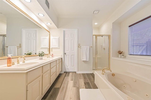 full bath with double vanity, a stall shower, wood finished floors, a jetted tub, and a sink