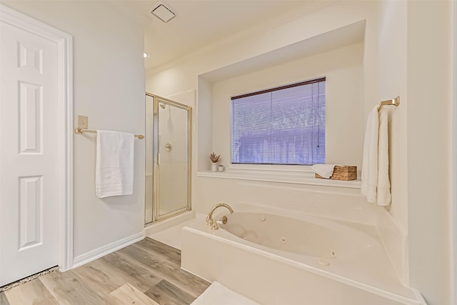 full bathroom featuring baseboards, a shower stall, a tub with jets, and wood finished floors