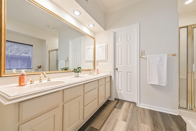 bathroom with double vanity, a stall shower, a sink, and wood finished floors