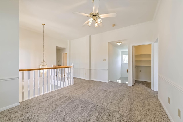 carpeted spare room with ornamental molding, baseboards, and a ceiling fan