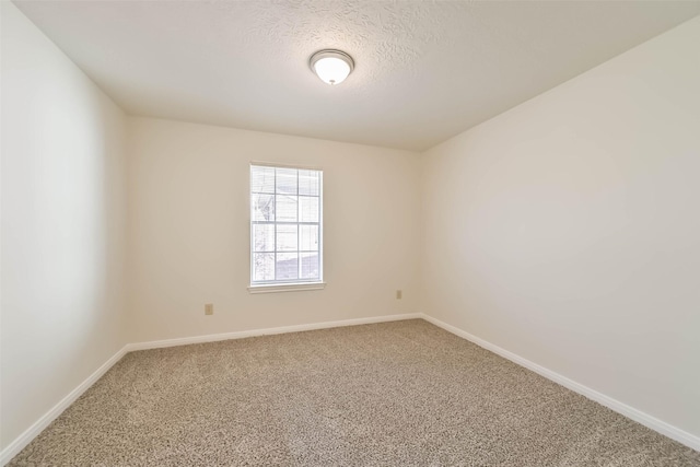 carpeted spare room with a textured ceiling and baseboards