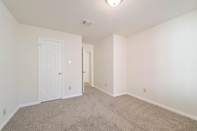 unfurnished bedroom with a textured ceiling, carpet, visible vents, and baseboards