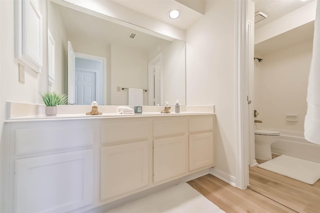 full bath featuring shower / bath combination, double vanity, visible vents, toilet, and wood finished floors