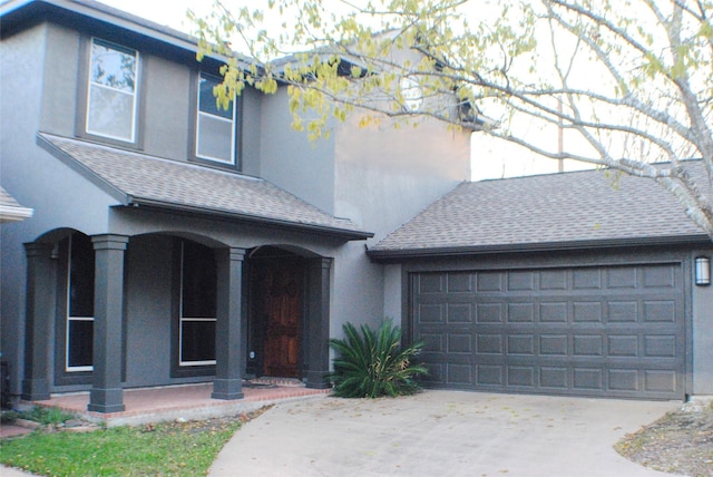 view of front facade featuring a garage, stucco siding, driveway, and roof with shingles