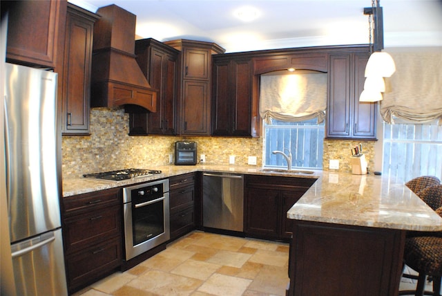 kitchen featuring light stone countertops, premium range hood, a peninsula, stainless steel appliances, and a sink