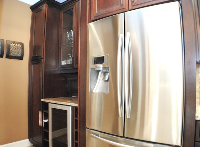 kitchen with glass insert cabinets, wine cooler, dark brown cabinetry, light countertops, and stainless steel fridge