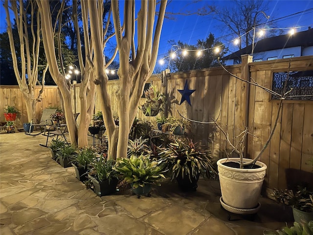 patio at night featuring a fenced backyard