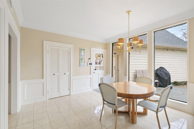 dining room with ornamental molding, light tile patterned floors, wainscoting, and an inviting chandelier