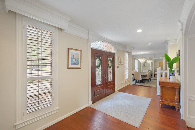 entryway with plenty of natural light, crown molding, baseboards, and wood finished floors