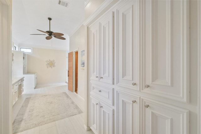 hall with light tile patterned floors, visible vents, and crown molding