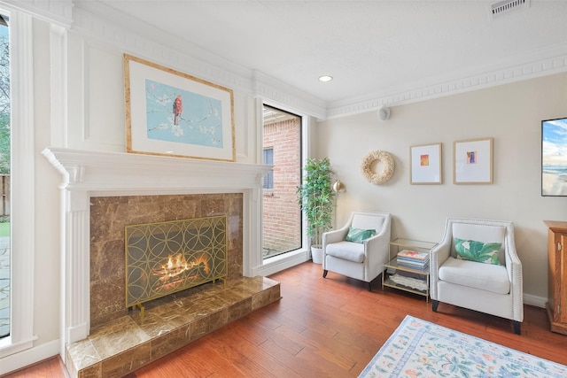 living area featuring crown molding, recessed lighting, visible vents, a high end fireplace, and wood finished floors