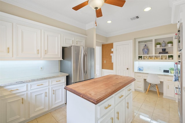 kitchen with light tile patterned floors, visible vents, built in study area, stainless steel appliances, and white cabinetry