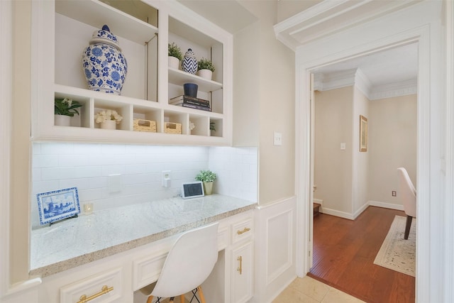 bar featuring crown molding, light wood-type flooring, built in shelves, built in desk, and backsplash