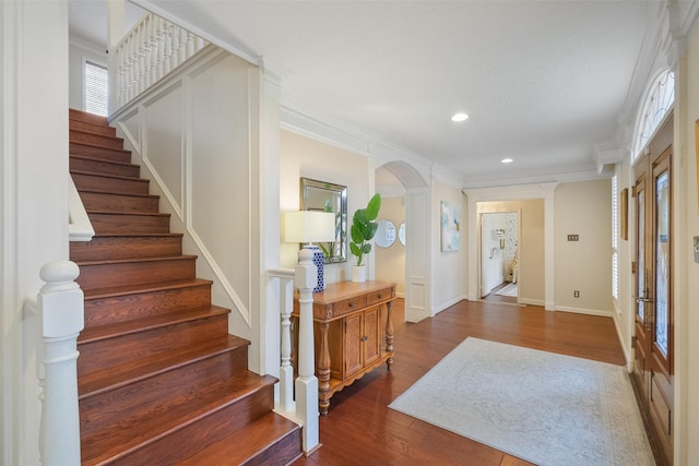 entrance foyer featuring arched walkways, dark wood finished floors, crown molding, and recessed lighting