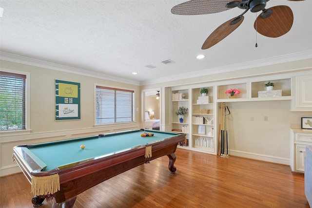 recreation room featuring light wood-type flooring, visible vents, crown molding, and a textured ceiling