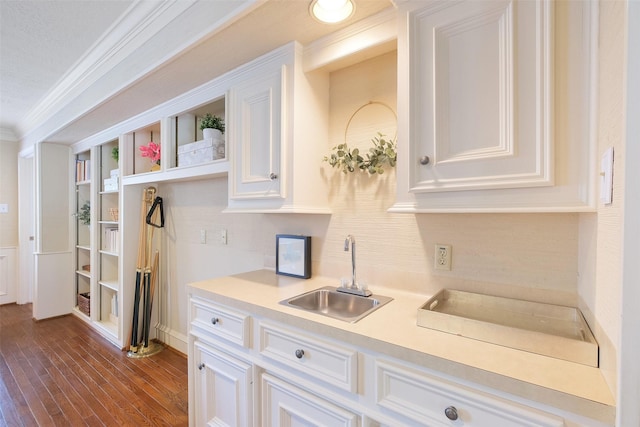 kitchen with white cabinetry, ornamental molding, light countertops, and a sink