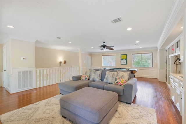 living area with hardwood / wood-style flooring, visible vents, and ornamental molding