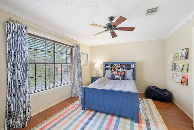 bedroom with ornamental molding, visible vents, and wood finished floors