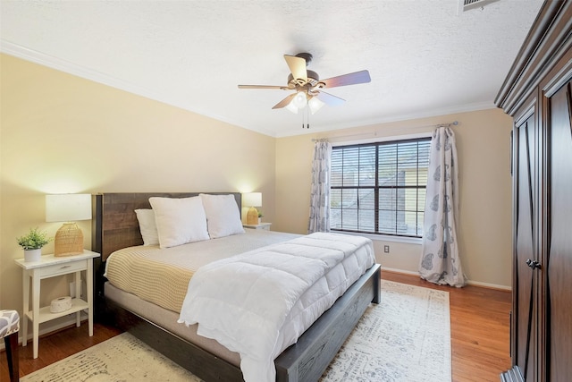 bedroom with baseboards, ceiling fan, ornamental molding, wood finished floors, and a textured ceiling