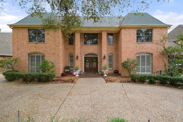 view of front of property featuring french doors, a shingled roof, and brick siding