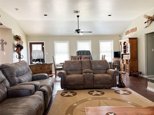 living area with visible vents, a textured ceiling, baseboards, and vaulted ceiling