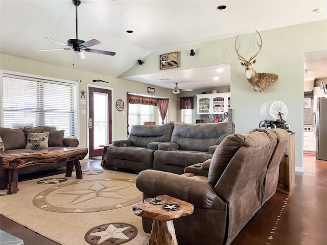 living area featuring a textured ceiling, a ceiling fan, and vaulted ceiling