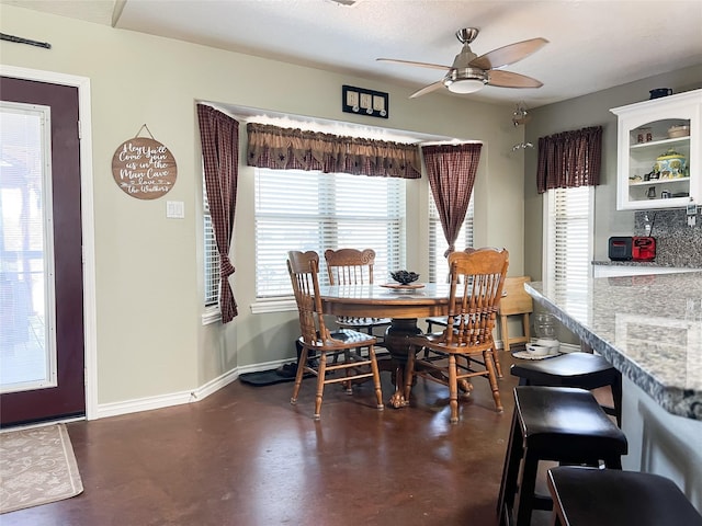 dining space featuring ceiling fan, baseboards, and finished concrete floors