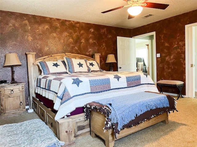 carpeted bedroom with visible vents, a textured ceiling, ceiling fan, and wallpapered walls