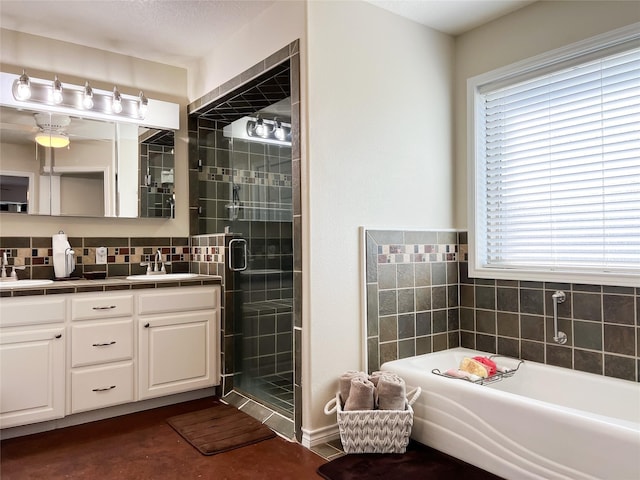 bathroom with a garden tub, double vanity, a shower stall, and a sink