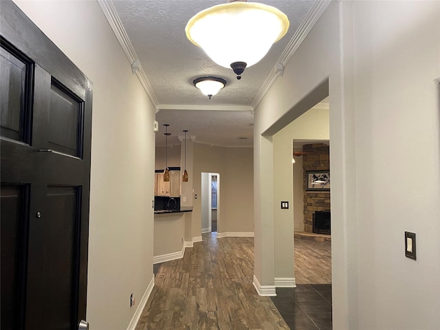 corridor with a textured ceiling, crown molding, baseboards, and dark wood-style flooring