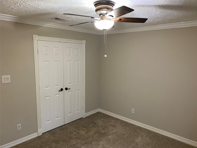 unfurnished bedroom with a closet, a textured ceiling, dark carpet, and crown molding