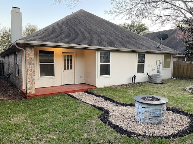 back of property featuring a shingled roof, a fire pit, fence, central AC, and a chimney