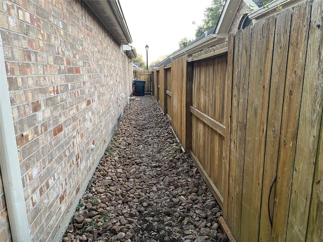 view of side of home with brick siding and fence