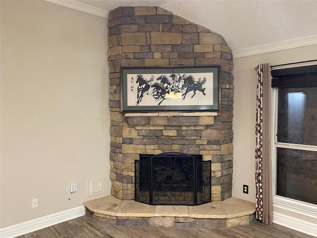 details with ornamental molding, a fireplace, a textured ceiling, and wood finished floors